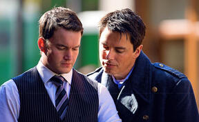 Ianto Jones and Jack Harkness from Torchwood looking at something together, standing side by side